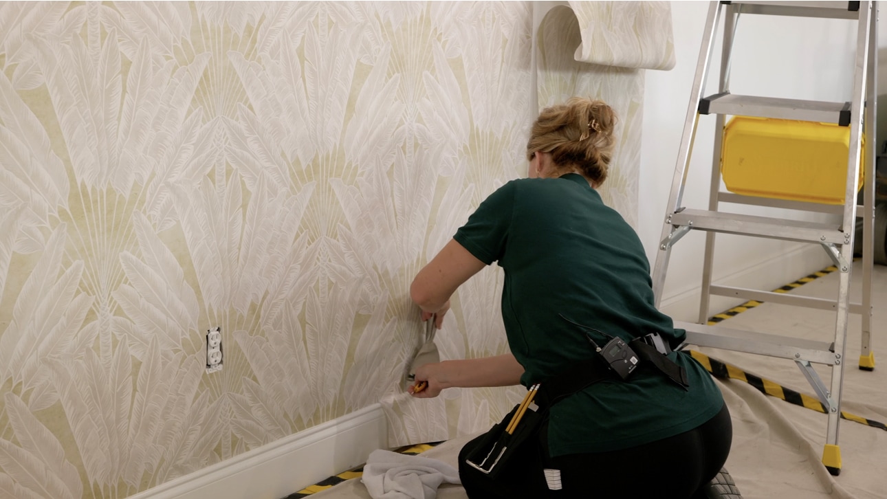 Professional wallpaper installer applying wallcovering to an interior wall